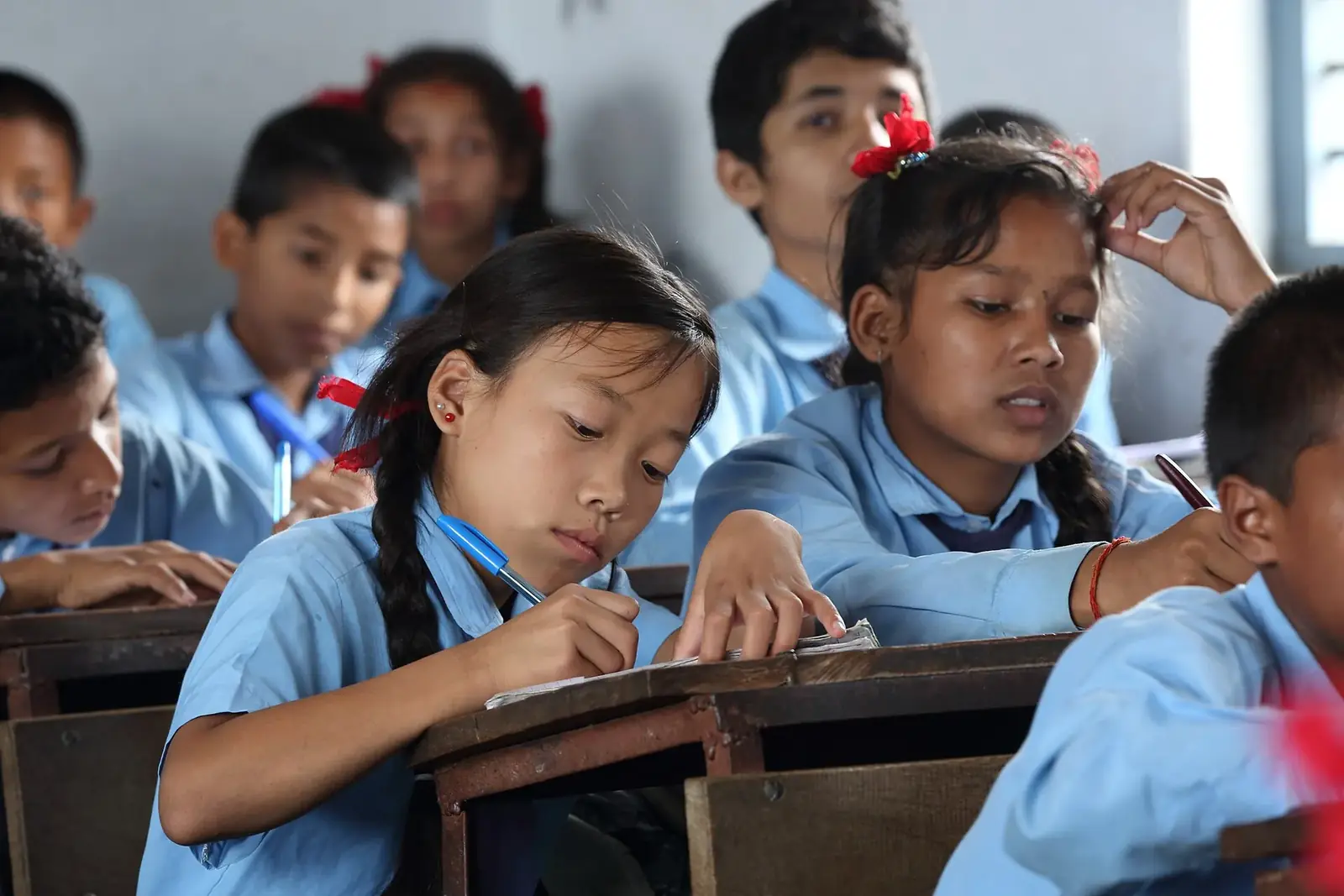 Students in blue uniforms working at their desks at Shree Dharmasthali school, a community school in Pokhara