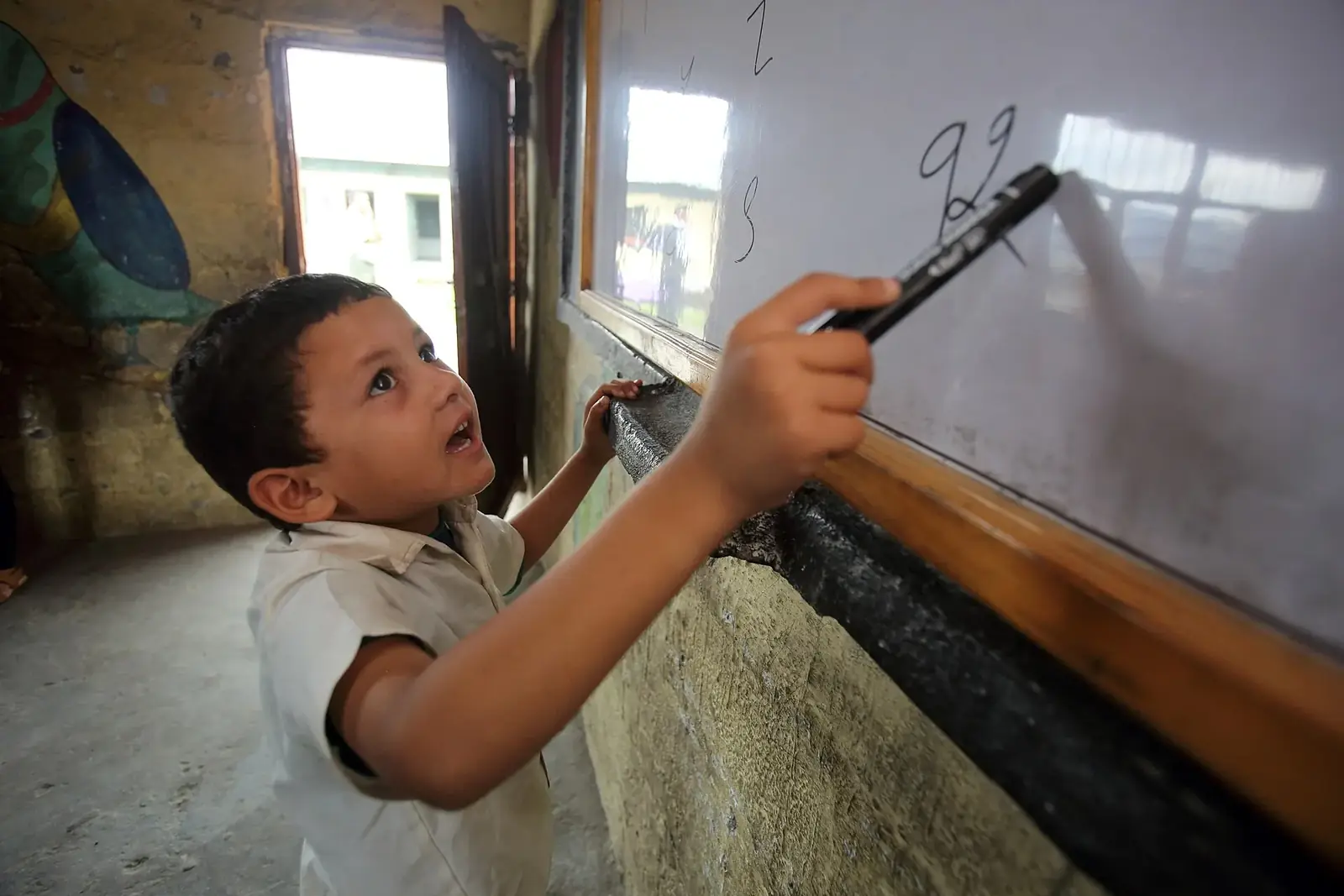A grade 1 pupil writing numbers on the whiteboard at Shree Sahara Bal Primary School, Pokhara