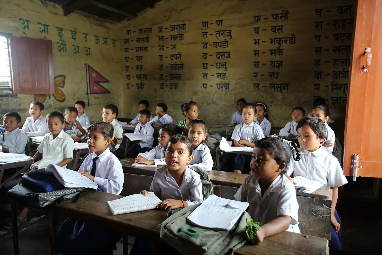 A grade 1 classroom at Shree Sahara Bal Primary School in Pokhara, pupils in white uniforms at wooden desks